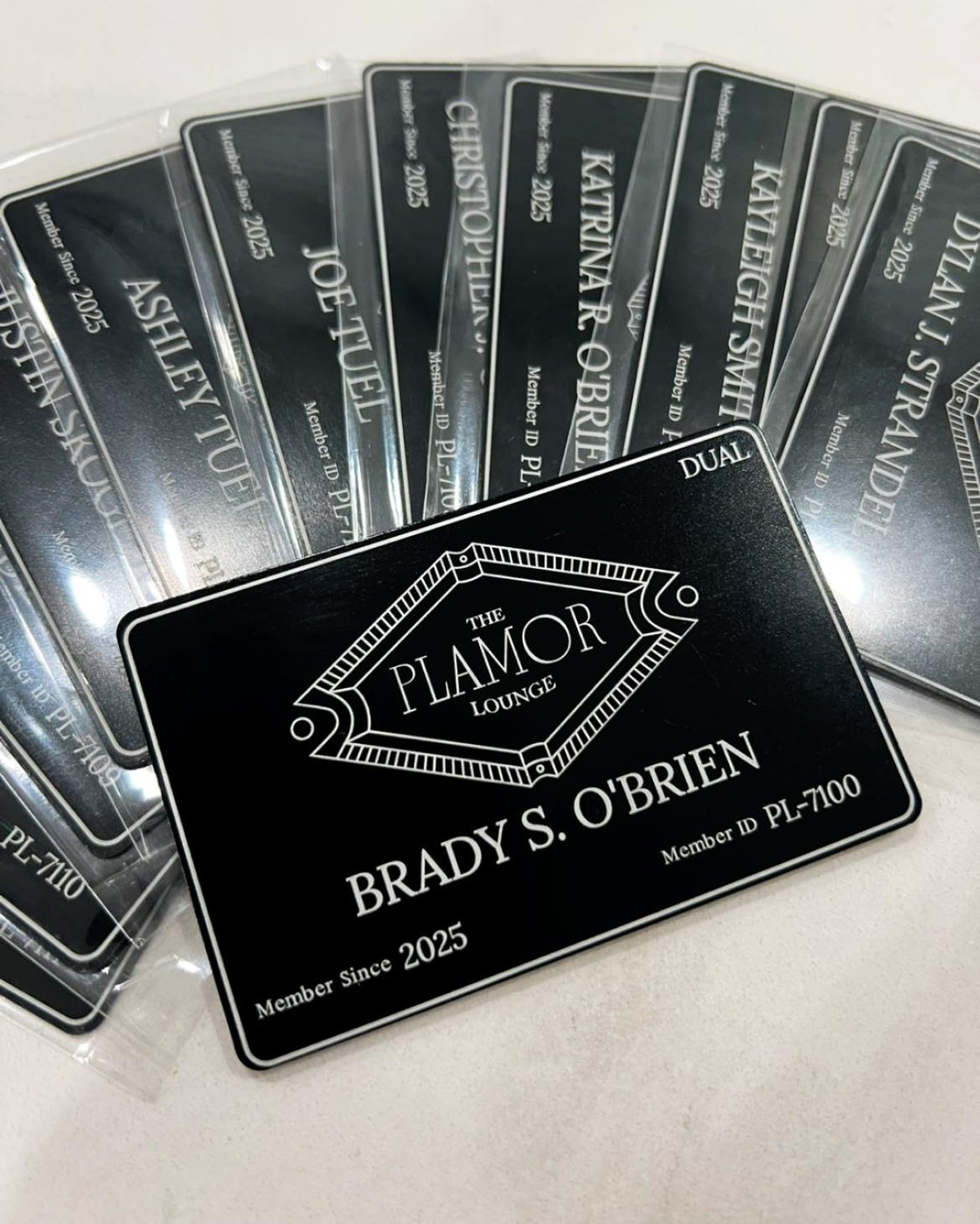 Engraved Plamor Lounge black metal membership cards with names and member IDs